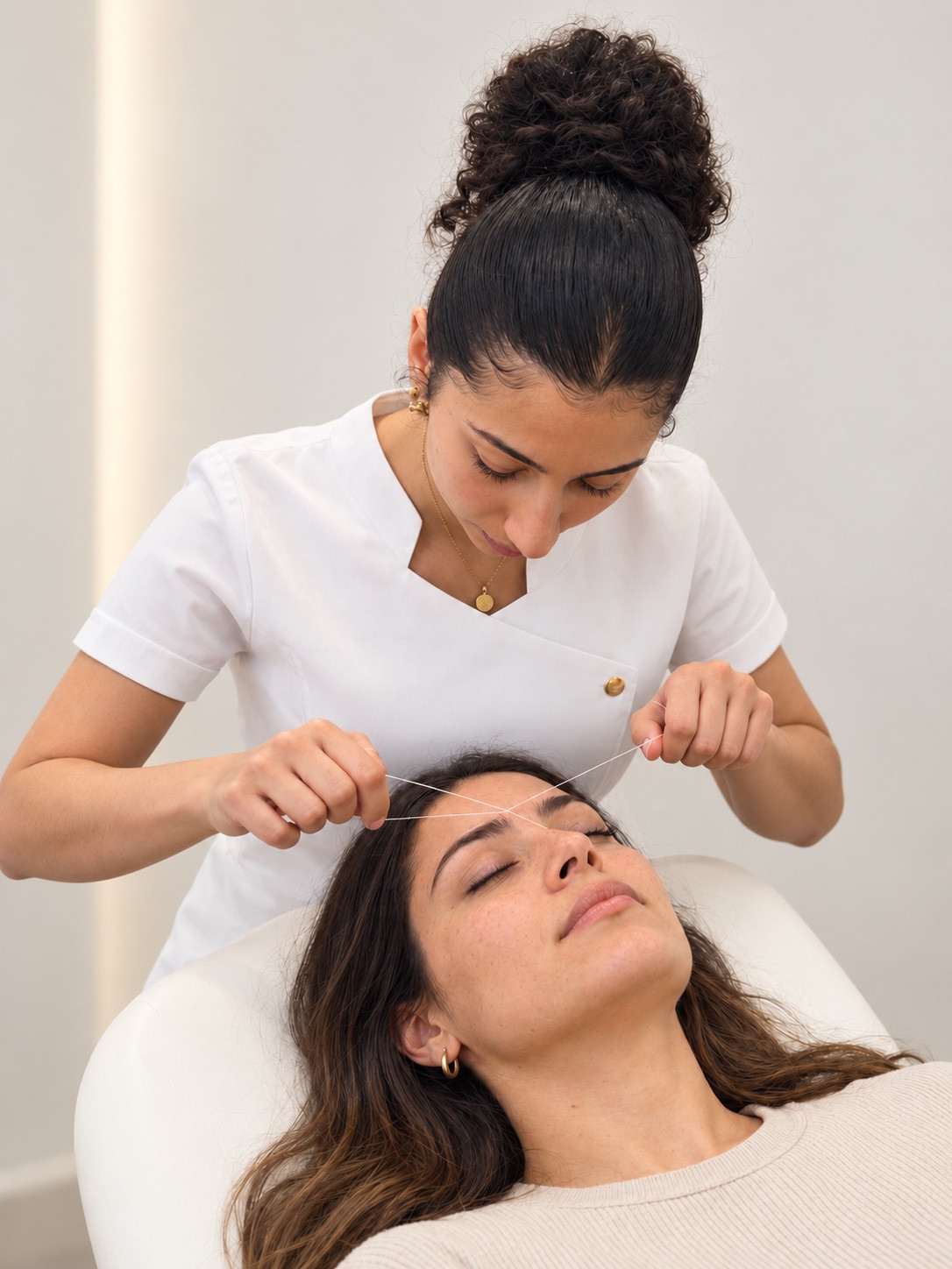 Sara using thread to shape a client’s eyebrows at ELKA CLINIC